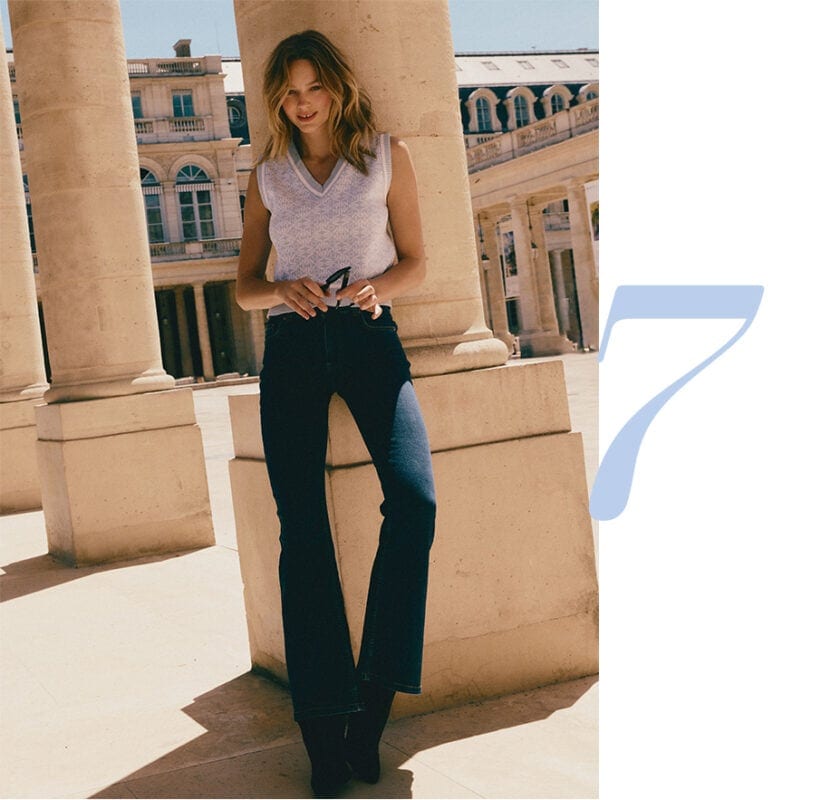 modelka w jeansach i dzianinowej kamizelce w monogram MOHITO opierająca się o kolumnę