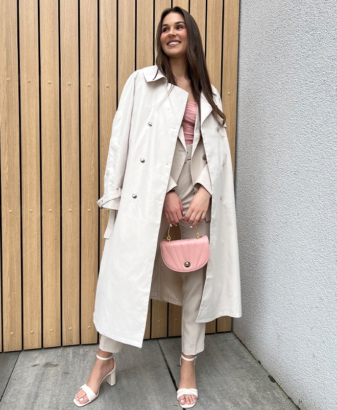 model zâmbitor în pantaloni bej și trenci cu brâu