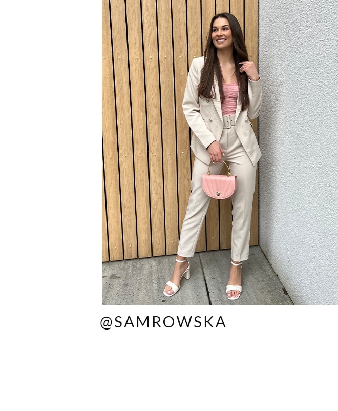 model într-un stil luminos, cu un top scurt, pantaloni morcovi și o geantă pastel