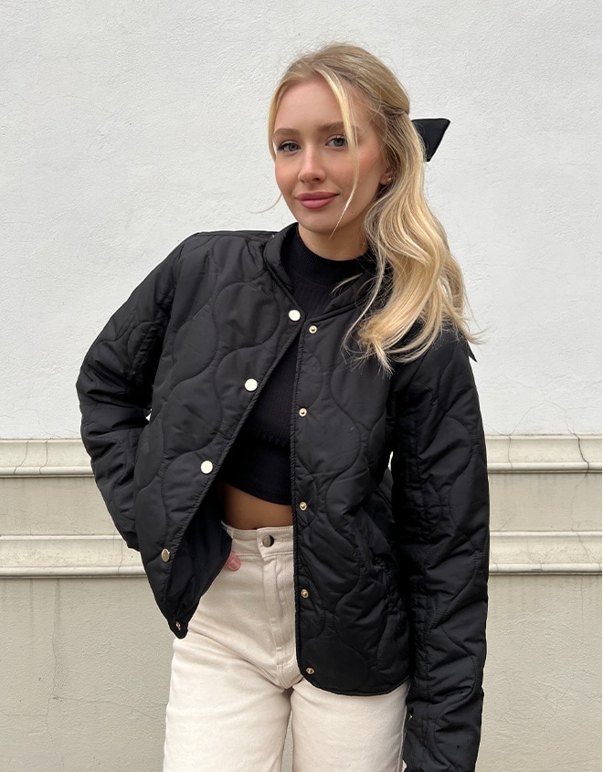 model in geaca matlasata neagra, blugi bej si top negru