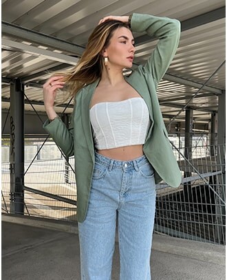 modelka w zielonej marynarce, dopasowanym topie i jeansach