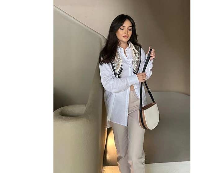 model în cămașă albă oversize, pantaloni bej și geantă de umăr