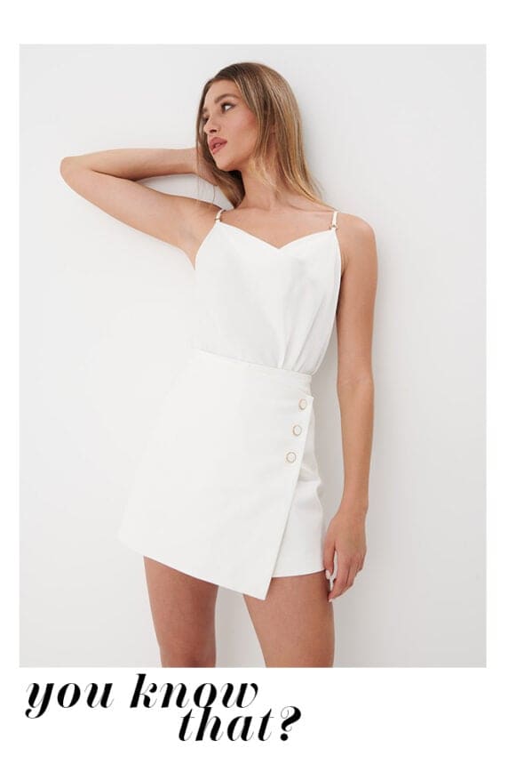 model într-un set alb: top cu bretele și fustă scurtă-short