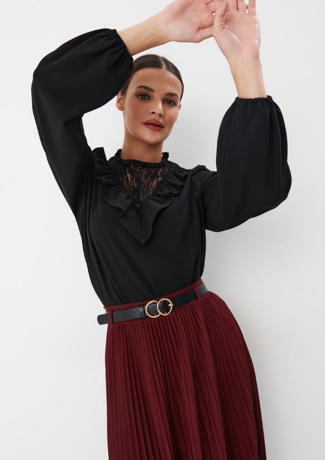 model într-o fustă midi plisată și o bluză neagră