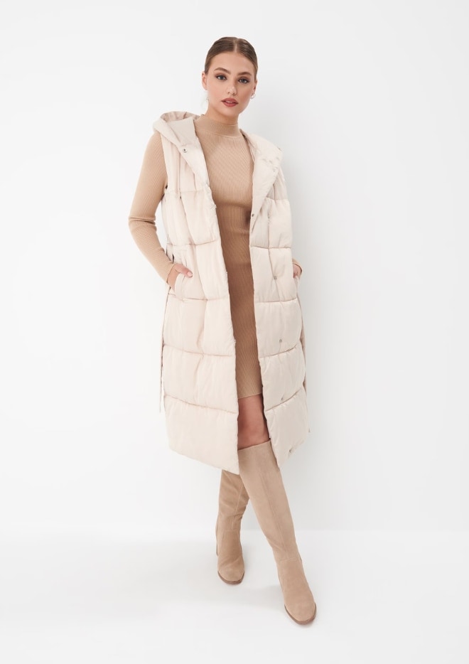model într-un stil luminos - o vestă lungă matlasată la modă, o rochie tricotată și cizme