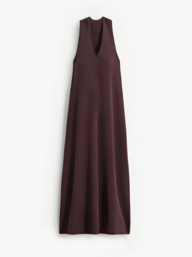 Minimalistyczna sukienka na wesele w duchu boho w kolorze ciemnego brązu. Prosty, luźny fason bez rękawów z głębokim dekoltem w kształcie litery V, wykonany z lekkiej, teksturowanej tkaniny nawiązującej do kolorów ziemi.