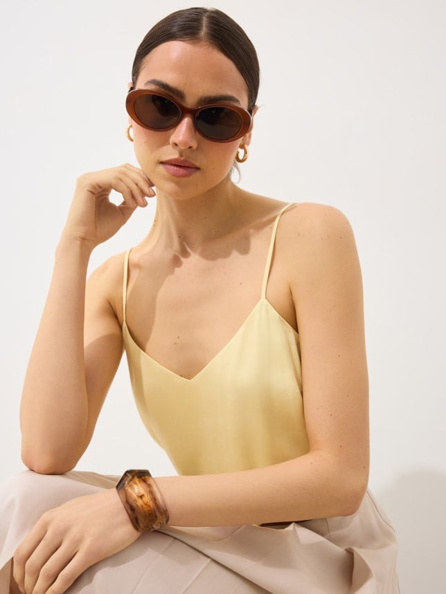 Modelka w topie w kolorze butter yellow i w okularach przeciwsłonecznych