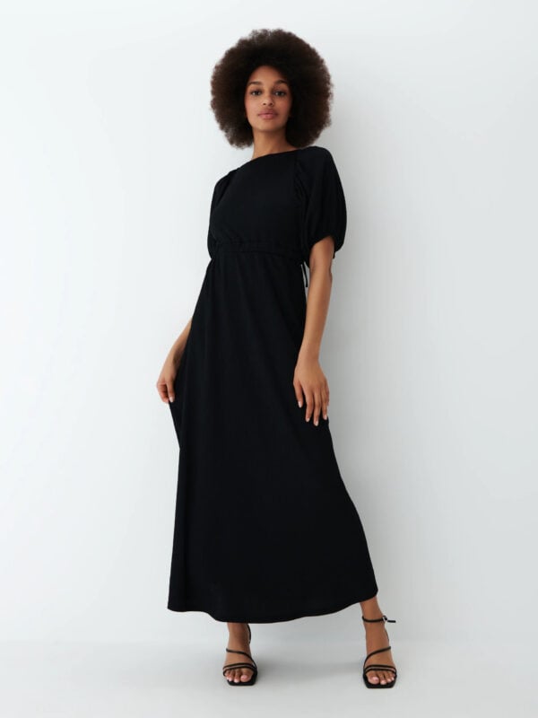 modelka z czarnymi włosami w ciemnej sukience o długości maxi