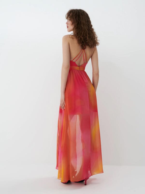 modelka prezentująca sukienkę w wyrazistych kolorach i efektownymi plecami 