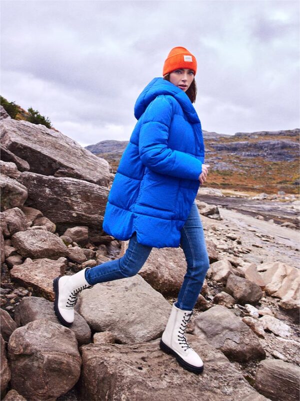 stylizacja z pomarańczowym swetrem, niebieską pikowaną kurtką i pomarańczową czapką typu beanie