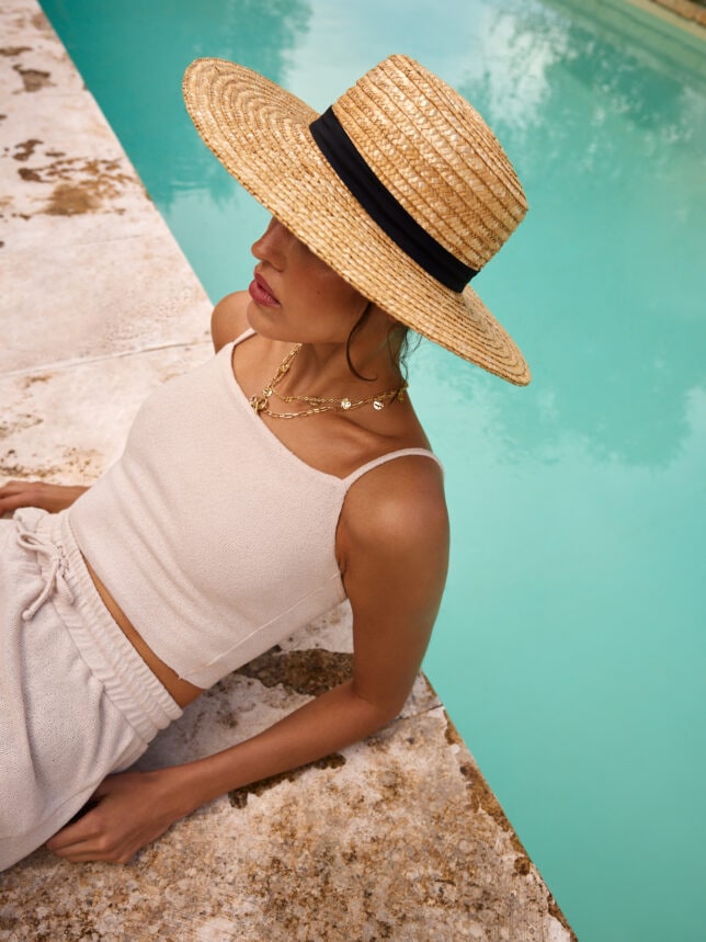 modelka w słomkowym kapeluszu i białym secie - perfekcyjnym na słoneczne podróże
