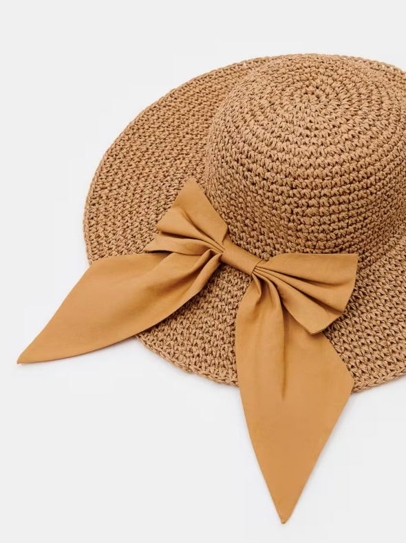 Kapelusz słomkowy z ozdobną kokardą.
