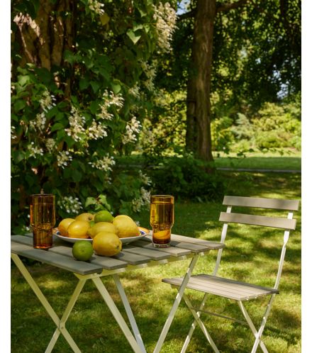 piękny ogród z krzesłem i stolikiem, a na nim cytryny i woda