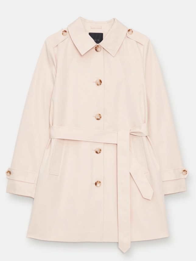 Jasnobeżowy krótki płaszcz typu trencz z paskiem i ciemnymi guzikami zaprezentowany na białym tle.