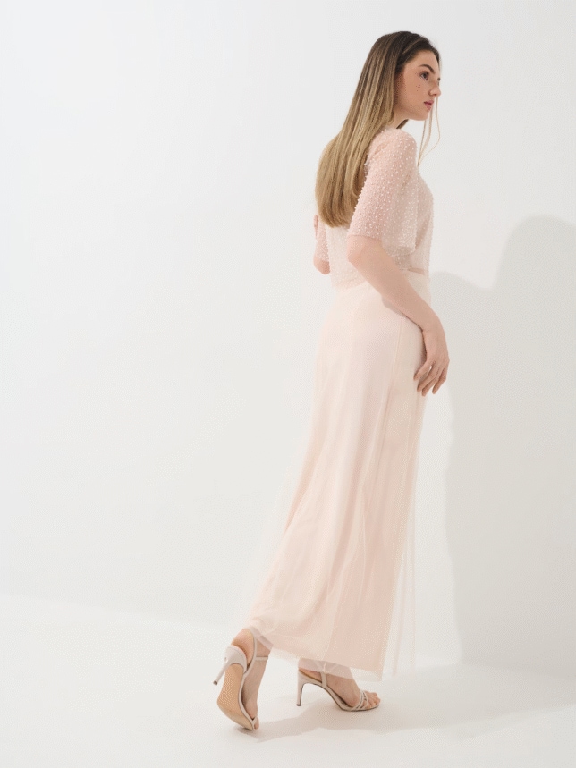 Spódnica o kroju litery A i długości midi, z wysokim stanem. Zdjęcie przedstawiające spódnicę od tyłu w połączeniu z butami na obcasie.