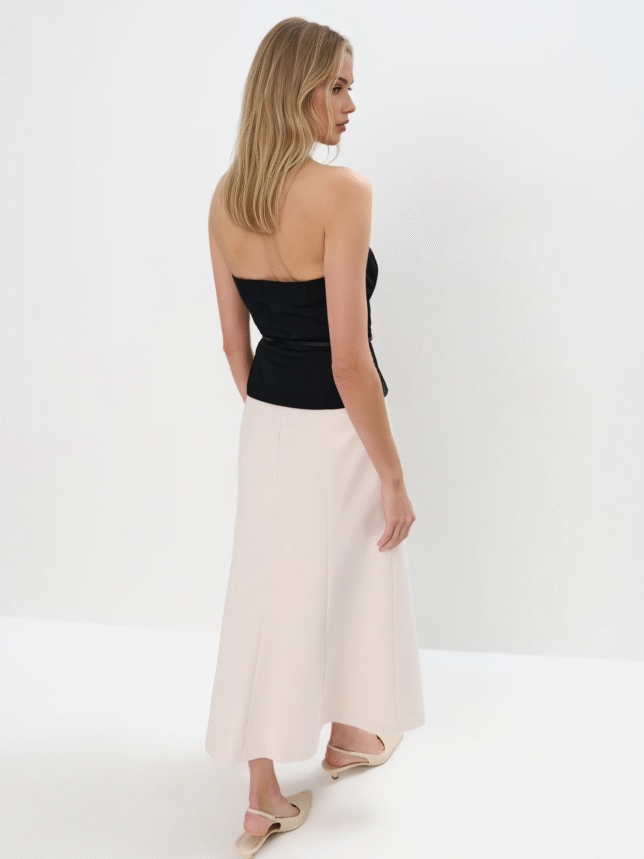 Kremowa spódnica midi w stylizacji z butami na obcasie i czarnym topem z paskiem.