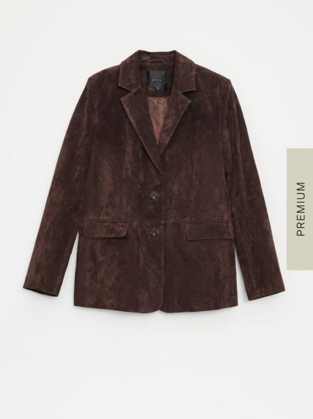Zamszowa marynarka o kroju oversize, w odcieniu czekoladowego brązu. Posiada zapięcie na dwa guziki.
