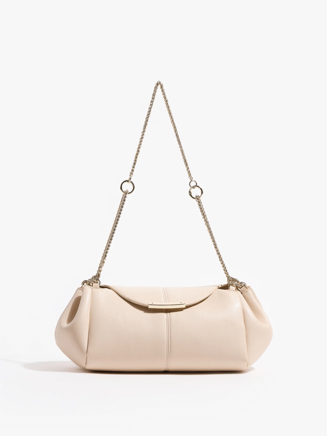 Jasnobeżowa, miękka torebka wieczorowa na złotym łańcuszku, ze złotą ozdobną blaszką na klapie.