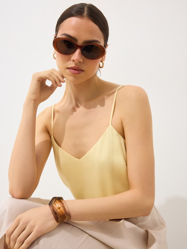 Modelka w topie w kolorze butter yellow i w okularach przeciwsłonecznych