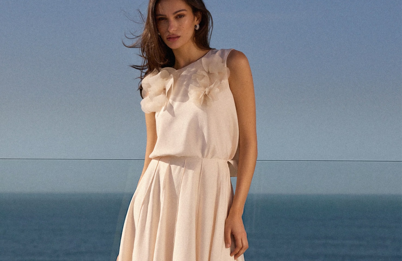 Modelka w komplecie bluzka + spódnica na wesele na tle morza.