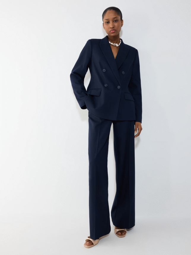 Stylizacja biznesowa lub na wesele: granatowy komplet , składający się z taliowanej marynarki i spodni typu wide-leg, uzupełniony sandałkami w kolorze beżowym.