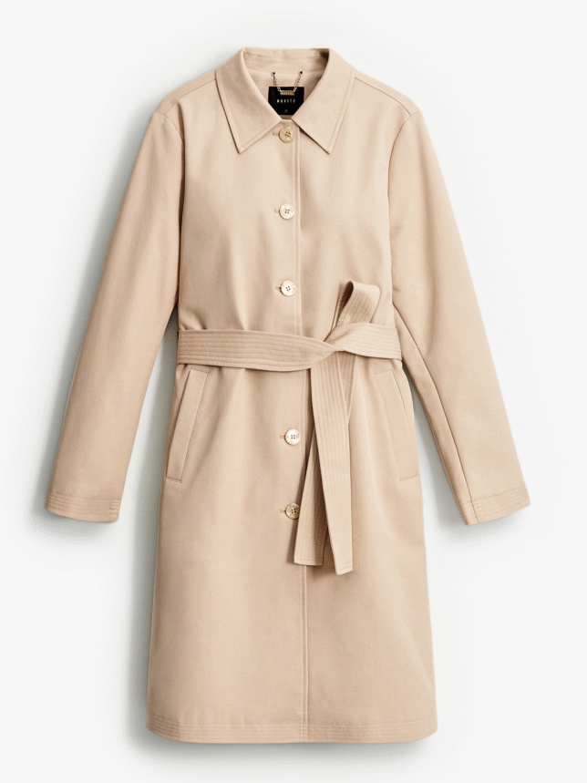 Beżowy trencz z zapięciem na guziki i wiązaniem w talii. Posiada dwie kieszenie boczne.
